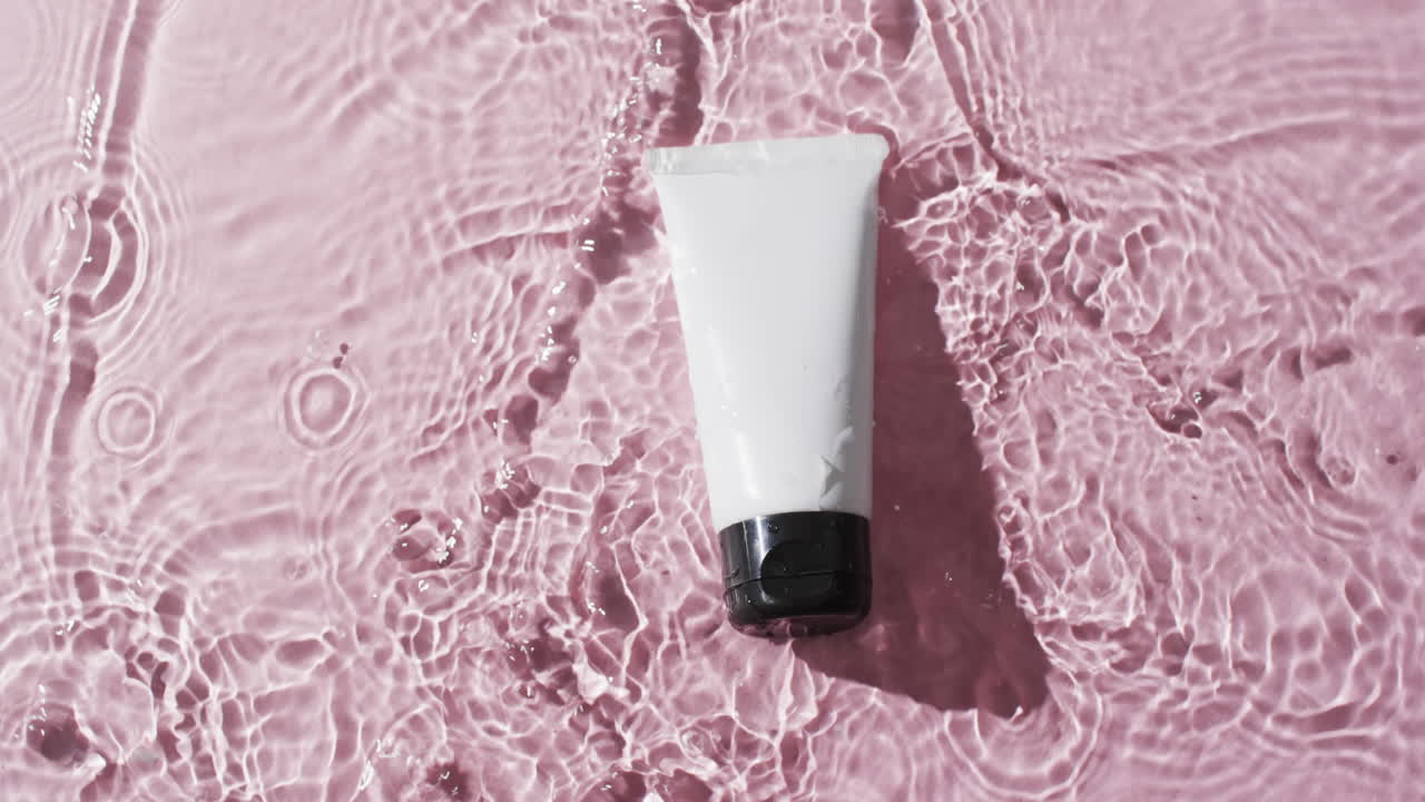 핑크색 배경에 복사 공간과 함께 물에 아름다움 제품 튜브의 비디오