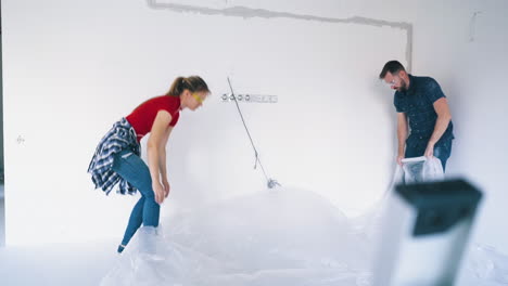 pretty-girl-and-boyfriend-puts-foils-on-floor-at-white-wall