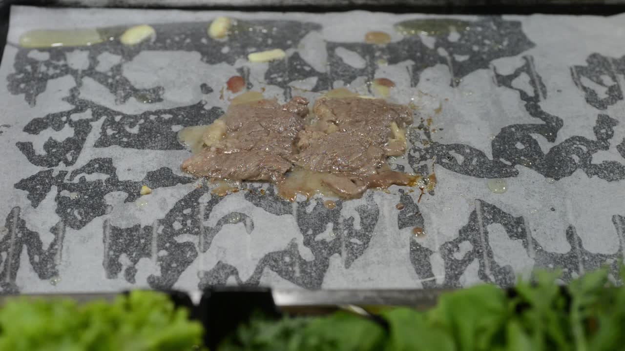Dünn geschnittenes Rindfleisch auf der Grillpfanne mit Backpapier.