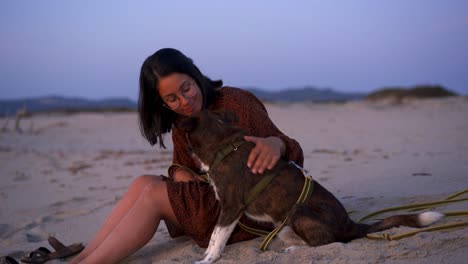 woman caressing and kissing dog on beach