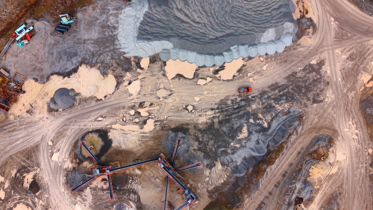 Top view of industrial quarry and conveyor system. High angle aerial shot of a stone quarry with conveyor belts, heavy machinery, and piles of gravel
