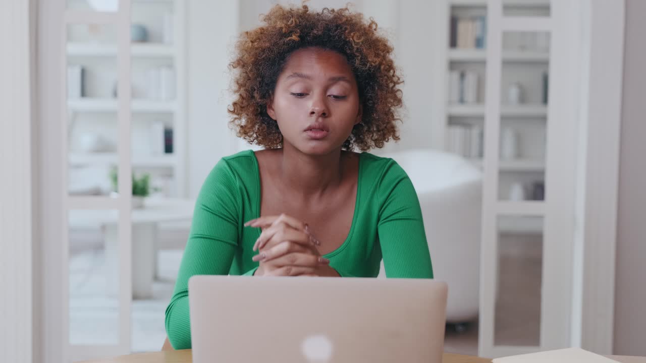 Young african american woman puzzled clutching head making video call on laptop
