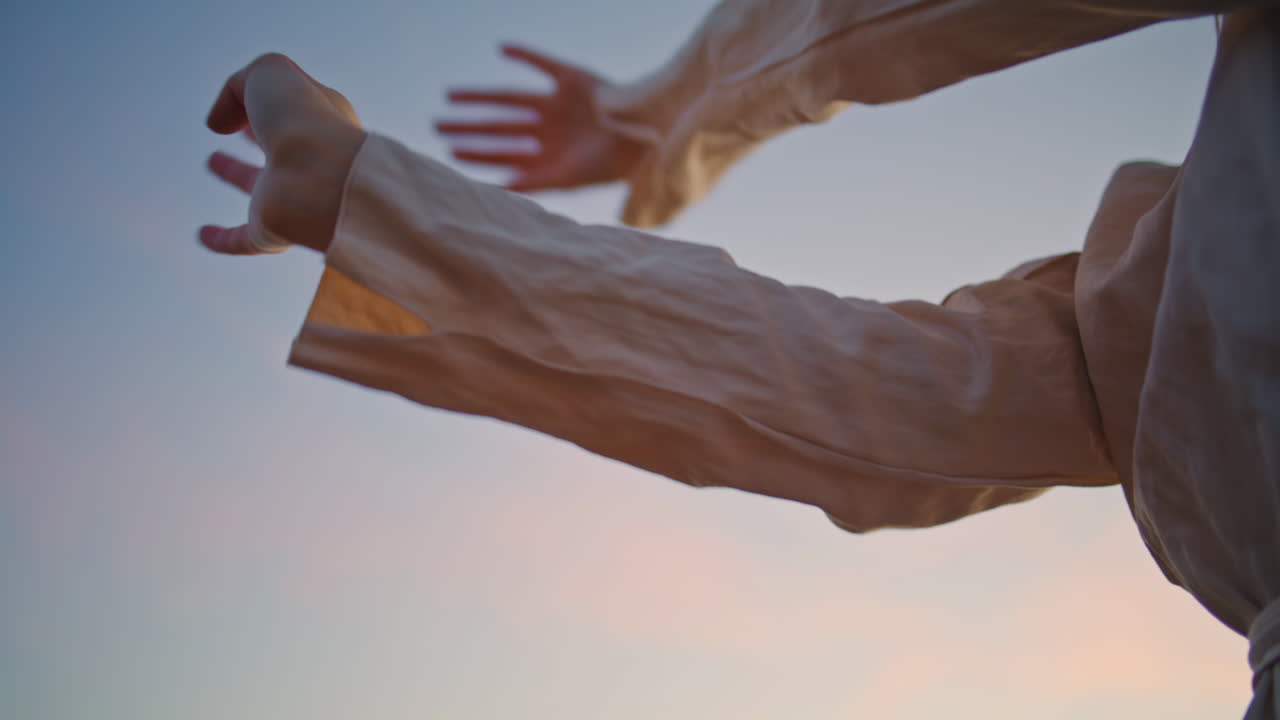 Closeup woman hands dancing doing smooth movements in sunset sky background