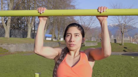 colocar mujer magra haciendo dominadas en el bar en el parque al aire libre