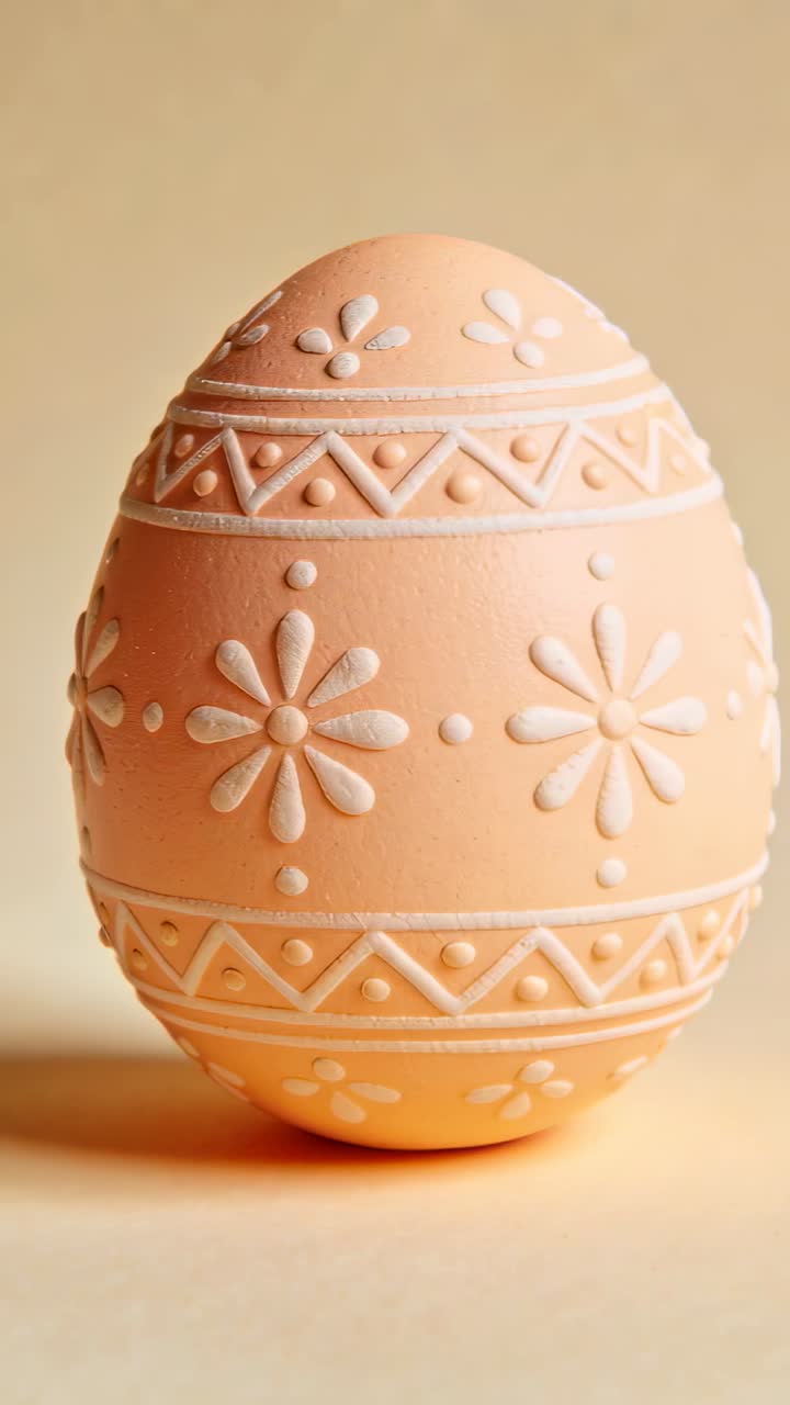 Carved egg rotating on beige tabletop and backdrop after camera pan, showing floral carvings