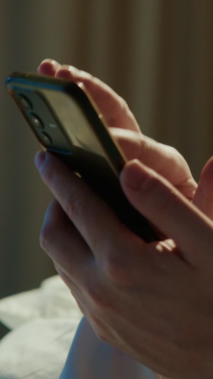 Hands interacting with a smartphone while relaxing at home in the evening