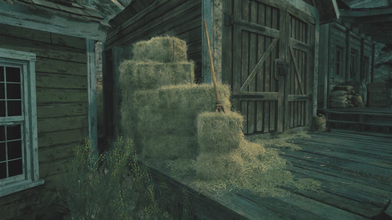 Stacked hay bales near wooden building in rural countryside at dusk