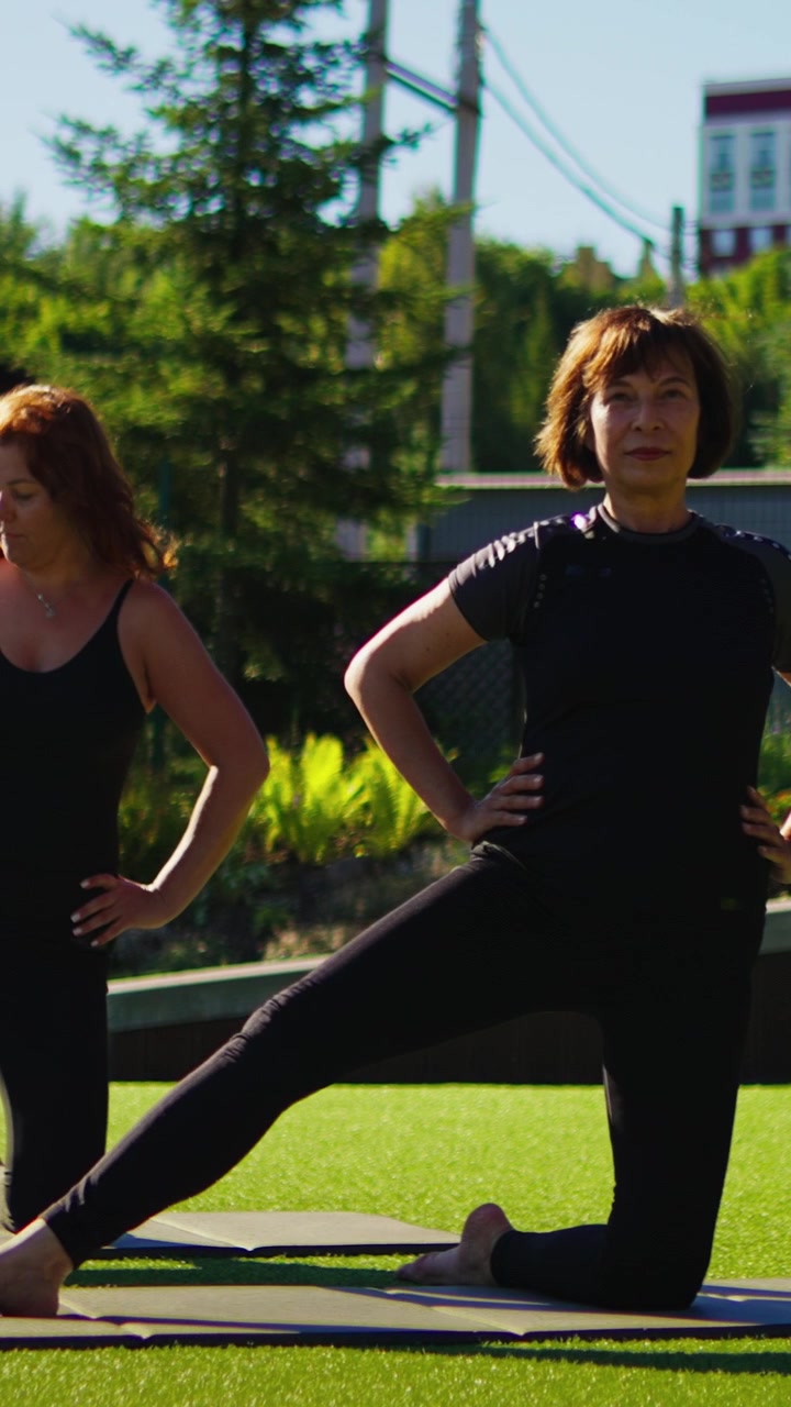 Donne mature che praticano posizioni yoga all'aperto in una giornata di sole