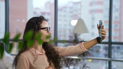 beautiful smiling lady having video call on her smartphone. pleasant talk on the phone in an office with large windows.