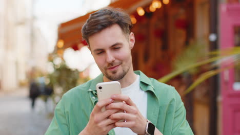 man using smartphone typing text messages browsing internet, finishing work, looking at camera