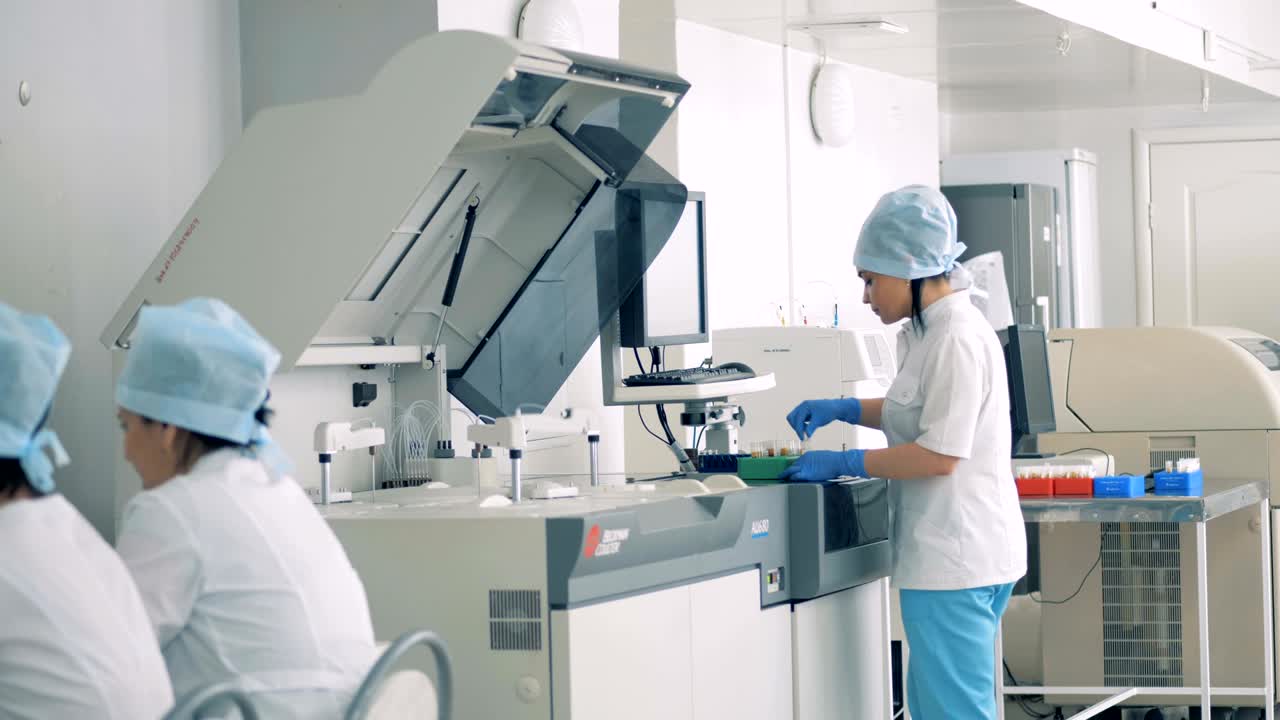 Automated laboratory equipment with workers at a production of medicines.
