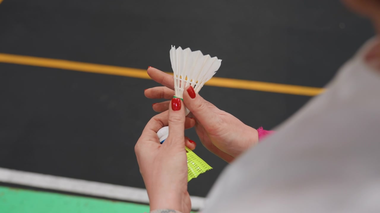 Donne che riparano un volano in dettaglio. Primo piano di mani che aggiustano con cura la testa del volano. Tutorial dettagliato su mani femminili che applicano nastro adesivo e ispezionano il sughero del volano sul campo