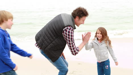 padre e hijos corriendo por la playa