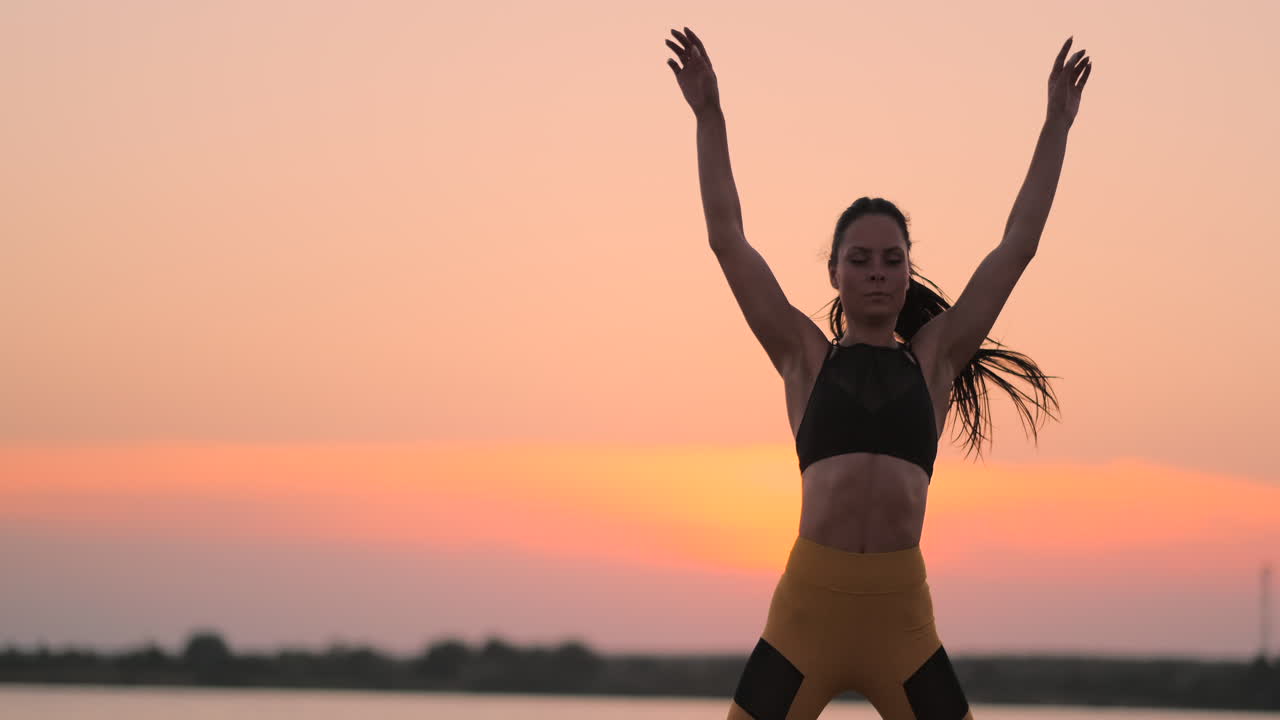 mujer de fitness feliz haciendo saltos o ejercicios de salto de estrellas en la orilla del mar al aire libre copia el espacio. niña trabajando en la playa en la mañana de verano retrato de longitud completa. concepto de estilo de vida saludable