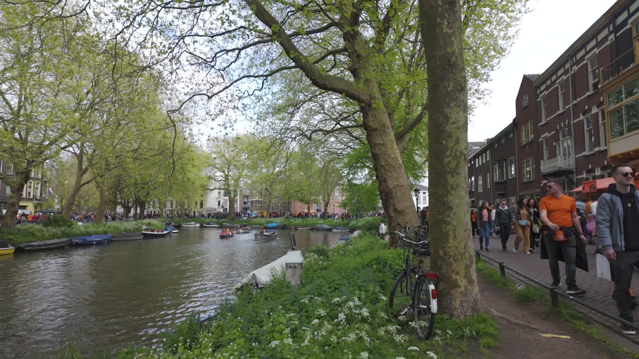 People celebrating Kings Day in Utrecht walking along a canal in the city center during the day