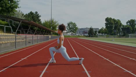 mujer estirándose en la pista de atletismo