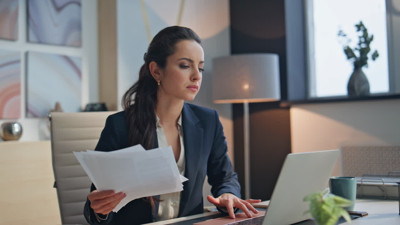 Upset businesswoman holding documents working computer desk at cabinet closeup