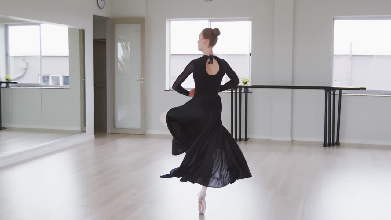Ballerina di danza classica caucasica che si esercita nella danza classica durante una lezione di danza in uno studio luminoso