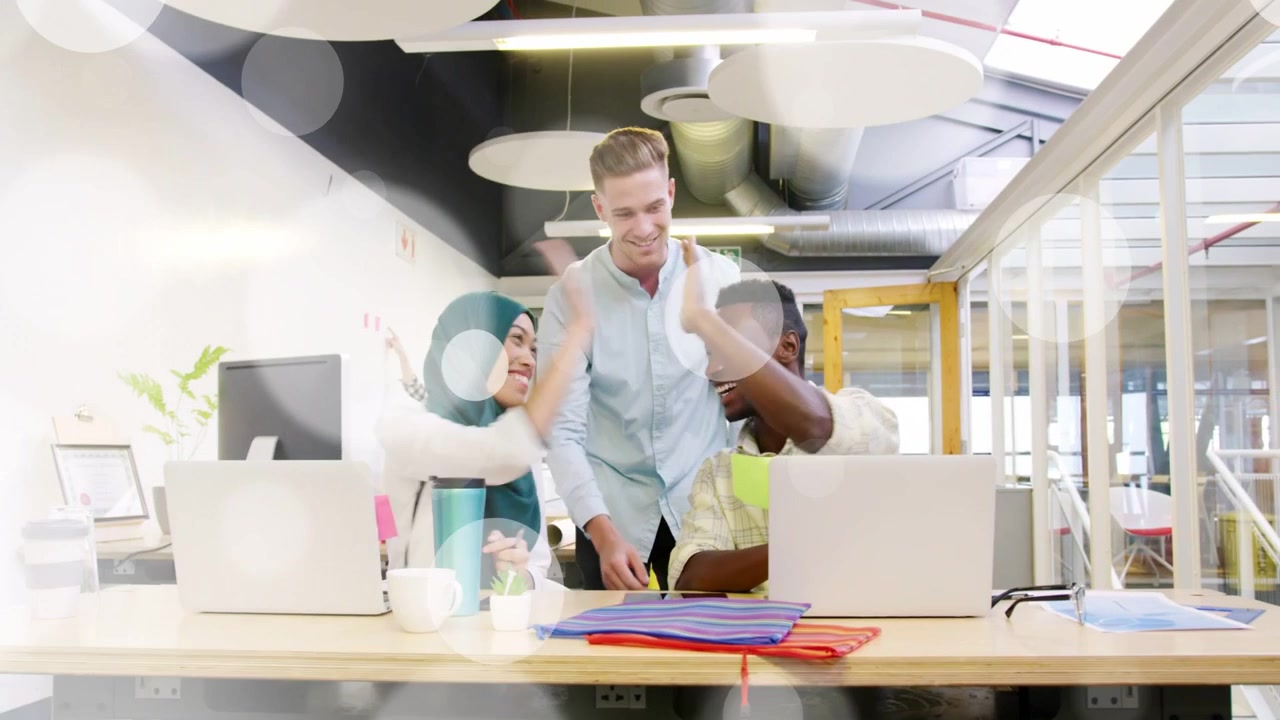 Man approaching table, pointing at laptop and notes, office team solving problem and high-fiving