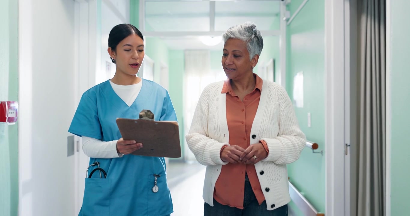 Nurse Discussing Medical Chart with Senior Patient in Hospital Corridor