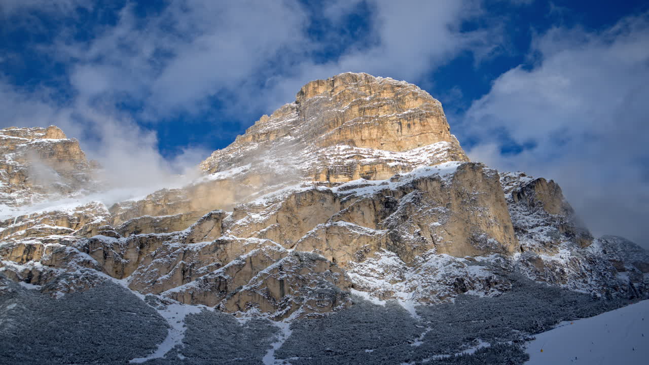 Distant view of snow on the trees and mountains in the Dolomites, Italy with the cloudy sky on the background