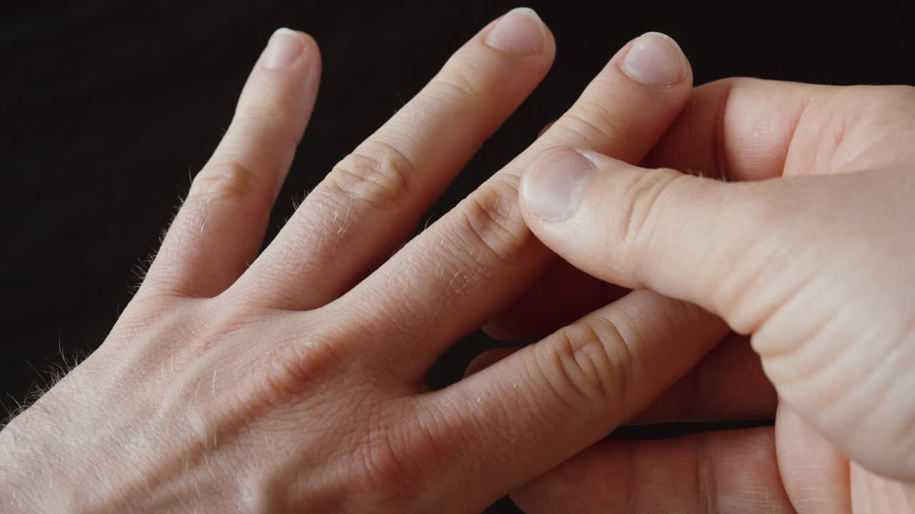 Close-up of a hand touching finger joints, representing pain, stiffness, and reduced mobility in the hand