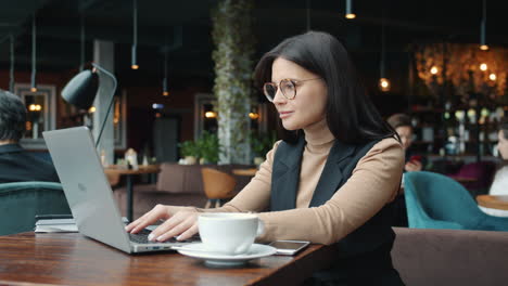 mujer trabajando en una computadora portátil en un café