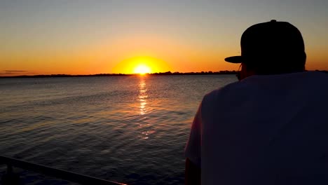 foto de seguimiento de un hombre mirando el río al atardecer en una terraza