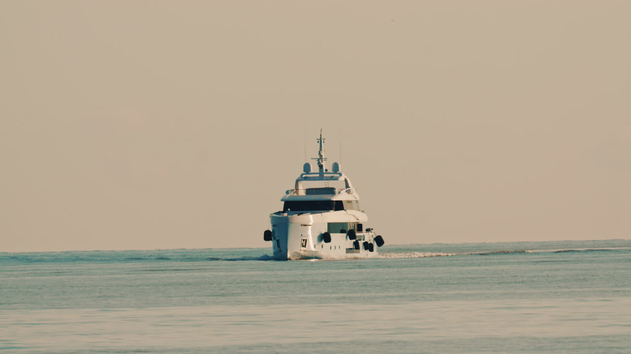 Vista frontale di un lussuoso yacht a motore che naviga lentamente in acque calme del Mediterraneo, con una boa di navigazione visibile nelle vicinanze