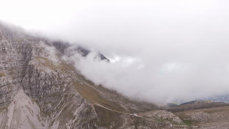 aerial establishing pullback of mount tymfi with cloudy sky, highlighting rocky cliffs and rugged mountain landscape