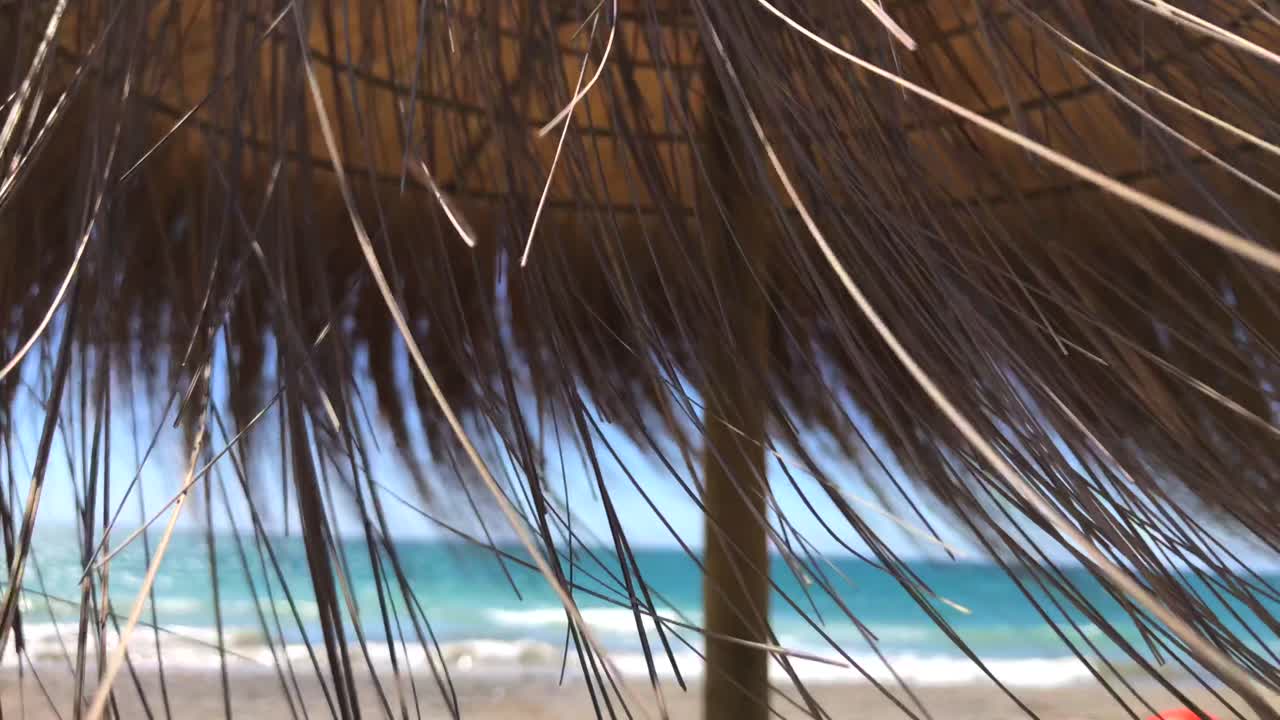 viento que sopla a través del paraguas tiki de paja en la playa en marbella malaga españa, vibraciones de vacaciones tropicales