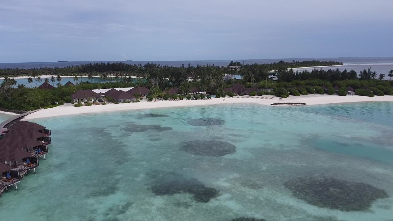 A stunning aerial rise over Haru Haru Island in the Maldives, revealing crystal-clear waters, white sandy beaches, and lush tropical scenery in this island paradise