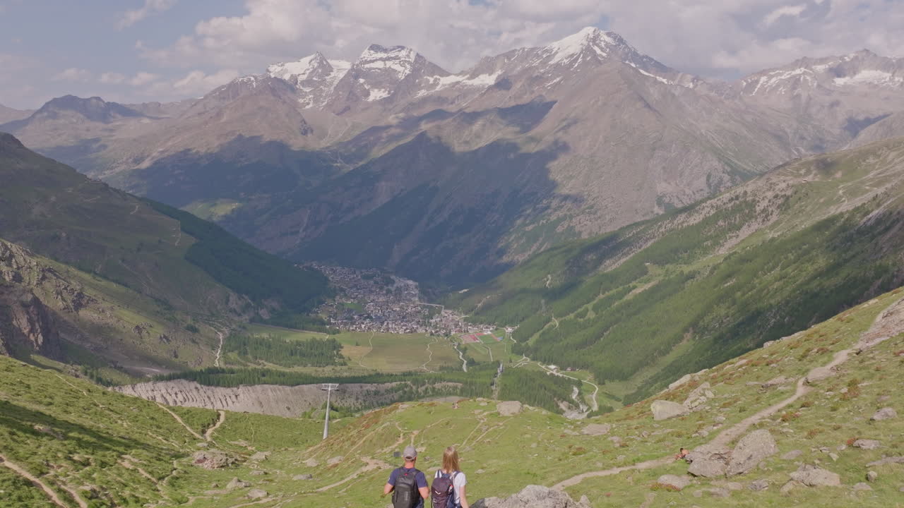 Two hikers explore Saas-Fee, Saas-Balen, and the Saas-Almagell dam, passing waterfalls, marmots, and alpine peaks in a breathtaking high-mountain landscape.
