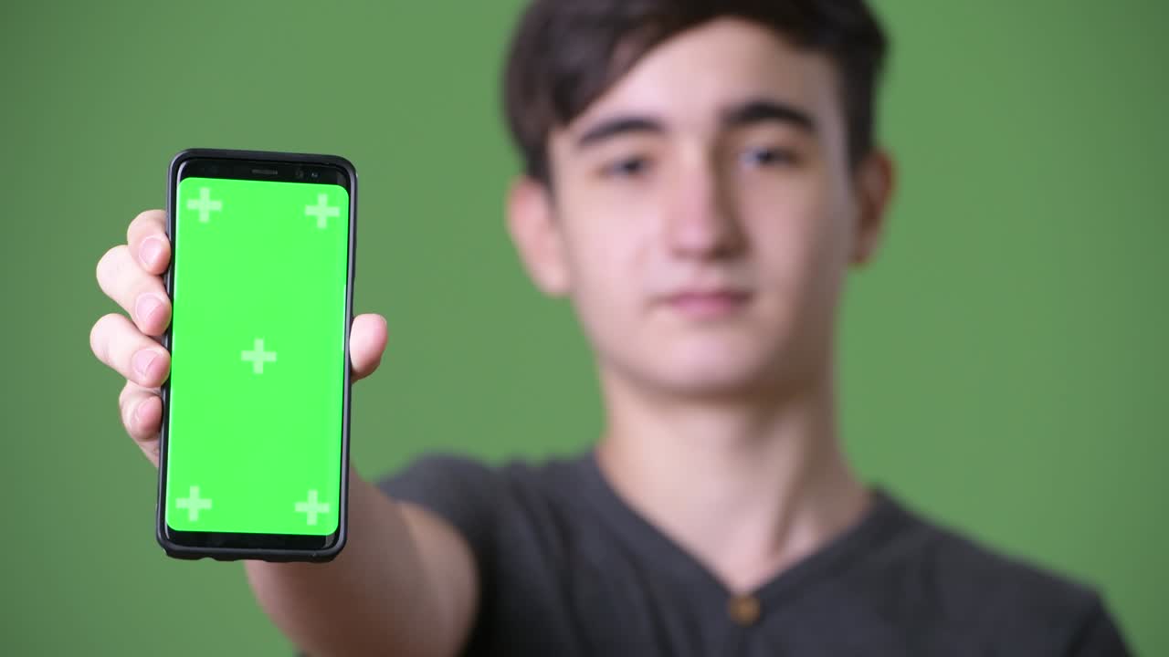 초록색 배경에 젊은 잘생긴 이란 십대 소년