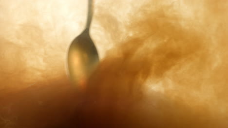 Macro-Shot-Of-Spoon-Mixing-Cloudy-Tea-Water-As-Colours-Infuse-Together