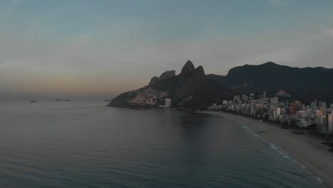 vista aérea de la montaña de los dos hermanos en el fondo con una playa casi vacía temprano en la mañana de ipanema en primer plano en río de janeiro al amanecer