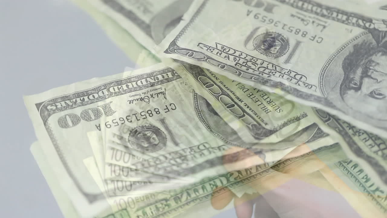 animación de billetes de 100 dólares que caen sobre la mano recortada sosteniendo y sacudiendo billetes de 100 euros.