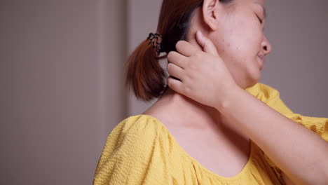 한 젊은 여성이 목 주위에 느지는 통증에서 벗어나기 위해 목을 마사지하면서 목을 고 있습니다.