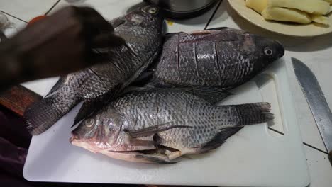 sazonar pescado tilapia con sal y pimienta en una cocina