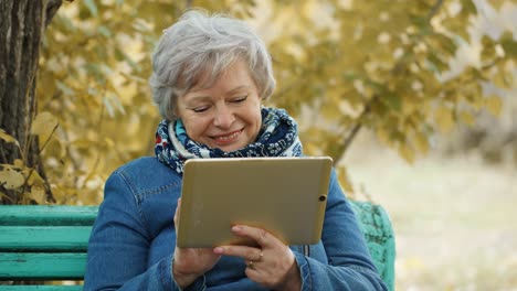 senior woman using tablet in autumn park