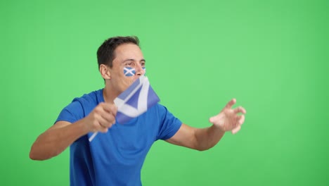 Man cheering for Scotland waving a national flag looking away