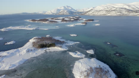 aerial view of a snow covered archipelago in the bright blue arctic waters of norway