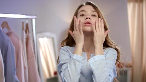 young woman face skin care. close up of pretty girl touching face with lotion