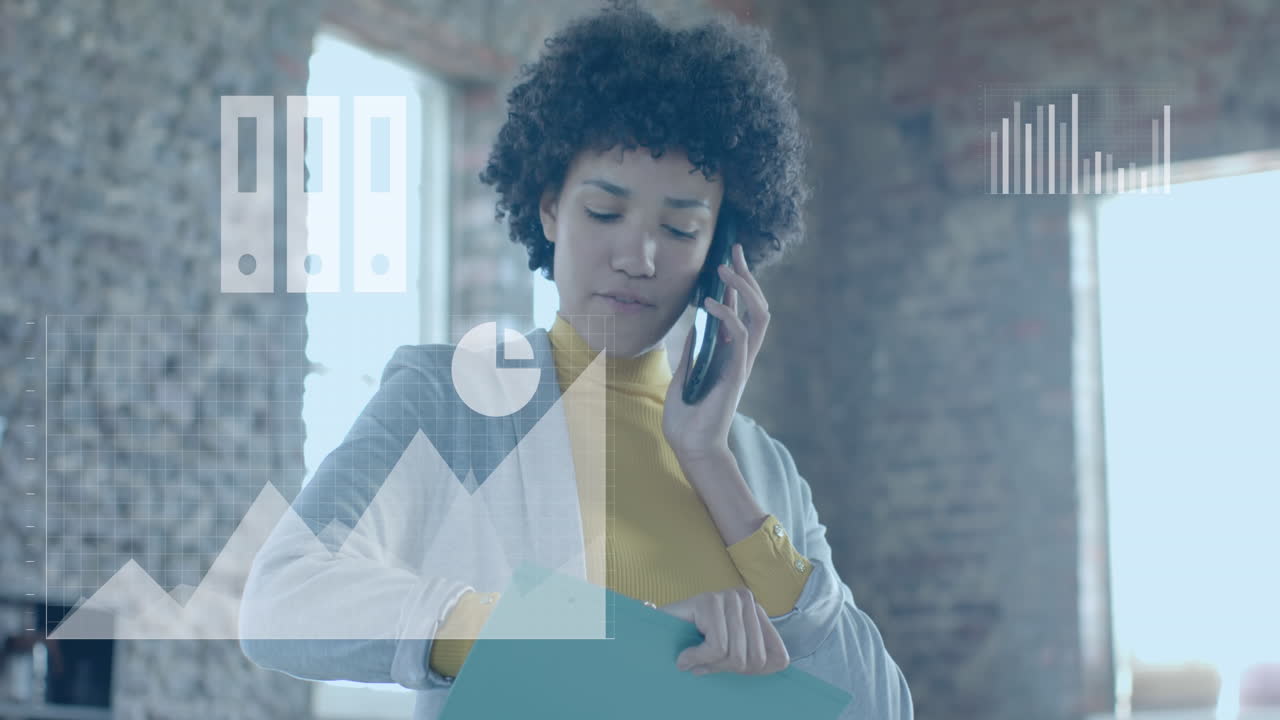Animation of business icons over biracial businesswoman talking on smartphone in office