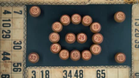 Cinematic-close-up-smooth-zoom-in,-shot-from-above-of-a-Bingo-wooden-barrels-in-a-circle,-woody-figures,-old-numbers-background,-vintage-board-game,-professional-lighting,-slow-motion-120-fps