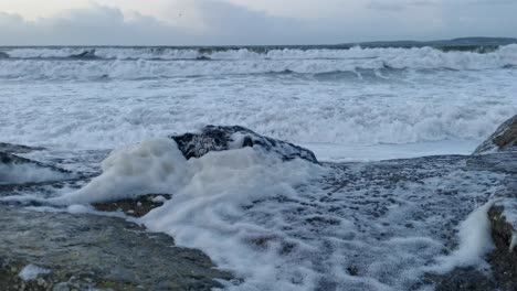 high spring tides and stormy weather waves with foam on rocks