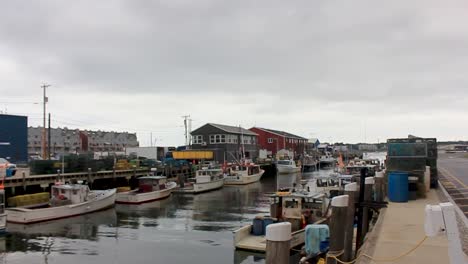 lobster boats sit idle in portland harbor, maine with building and lobster pots on the sides.