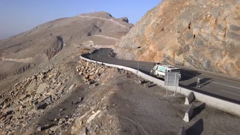 Fliegen-über-Die-Straße-Am-Jebel-Jais-Berghang-Mit-Touristen,-Die-Die-Aussicht-Genießen---Niedrige-Luftaufnahme