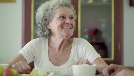 cheerful senior woman sitting at kitchen table and talking.