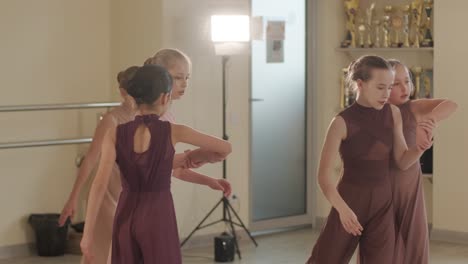 a group of young ballet students in black dancewear practicing positions in a spacious ballet studio with wooden flooring and wall-mounted barres. focused expressions and synchronized movements.